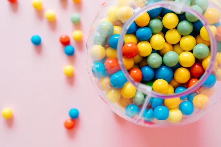 Glass gumball machine overflowing with vibrant candies